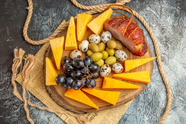 Overhead view of best snack with various fruits and foods on a wooden brown tray rope on an old newspaper