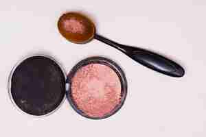 Free photo an overhead view of black oval brush and compact face powder isolated on white backdrop