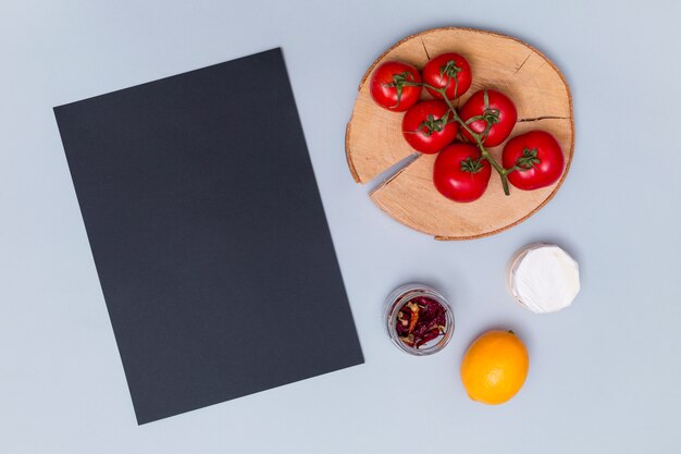 Overhead view of black slate with tasty tomato; dried chili; and lemon