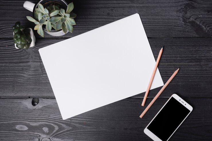 Free Photo an overhead view of blank paper with two colored pencils and smartphone on wooden table