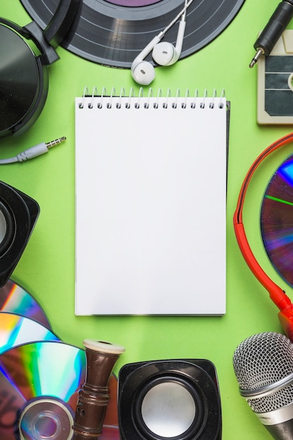 Free photo an overhead view of blank spiral notepad with audio equipments