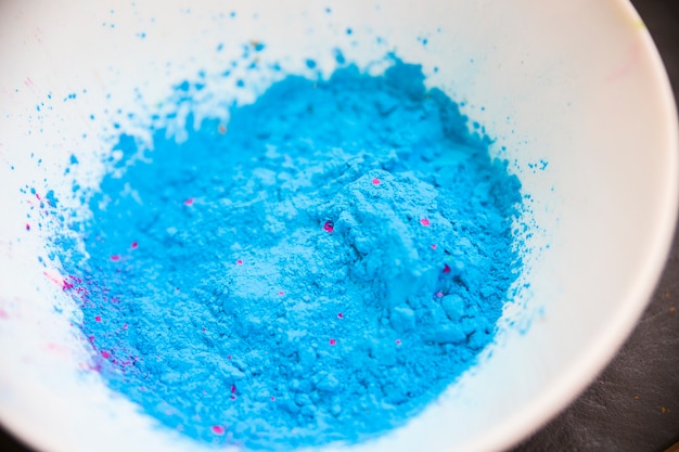 An overhead view of blue colored powder in the white bowl