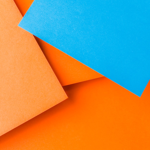 Free photo an overhead view of blue craft paper over the plain orange background
