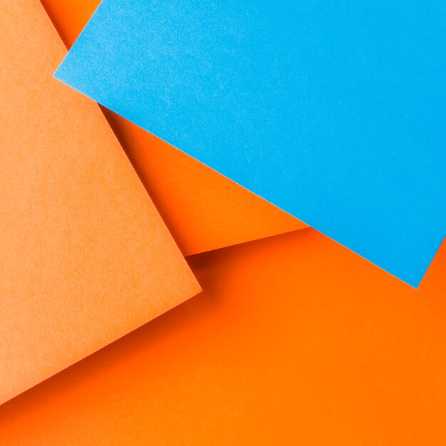 An overhead view of blue craft paper over the plain orange background