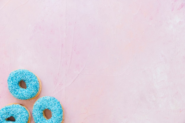 Overhead view of blue donuts on pink background