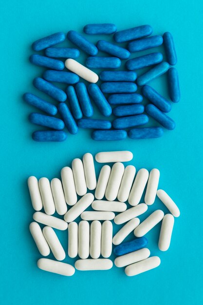Overhead view of blue and white candy capsules on cyan background