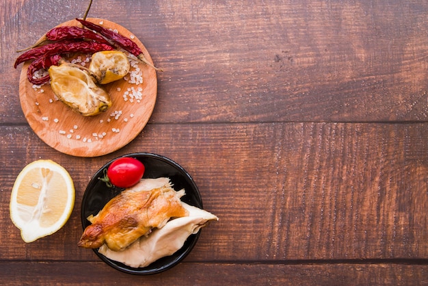 Overhead view of boiled and roasted chicken with ingredients over wooden desk