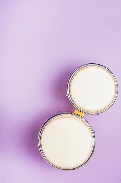 An overhead view of bongo drum on purple background