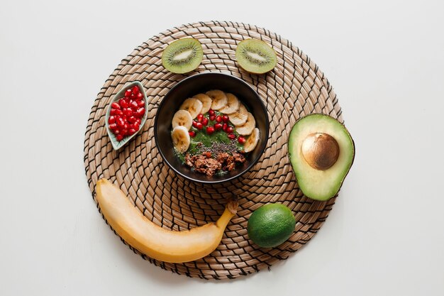 Overhead view of bowl topped with avocado and spinach, pomegranate seeds and granola