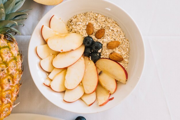 An overhead view of bowl with apple slices blueberry and almond with oatmeal