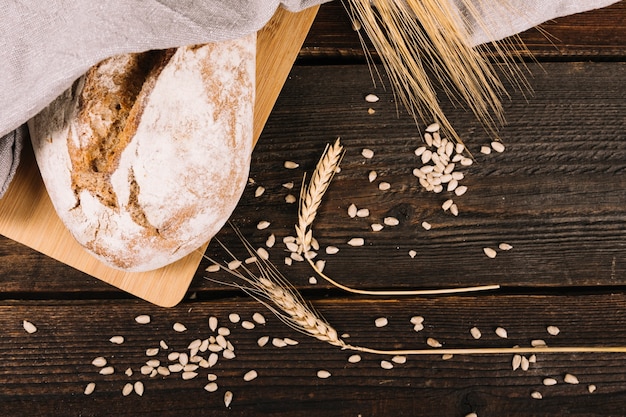 Верхний вид хлеба и уха пшеницы с семенами подсолнечника на деревянном столе