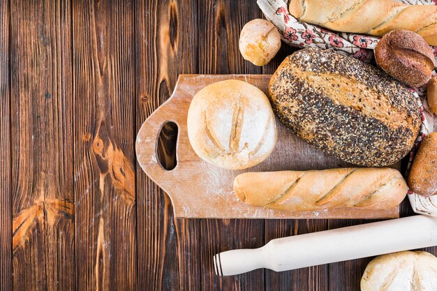 Overhead view of bread loaves on chopping board over the wooden table