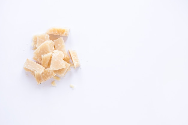 An overhead view of broken cheese isolated on white background