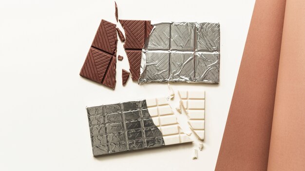 An overhead view of broken white and brown chocolate bar against white background