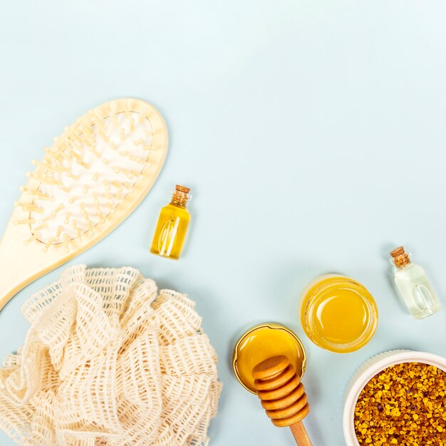 Overhead view of brush; essential oil bottle; honey jar; bee pollen and loofah