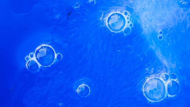 An overhead view of bubbles over the blue paint textured background
