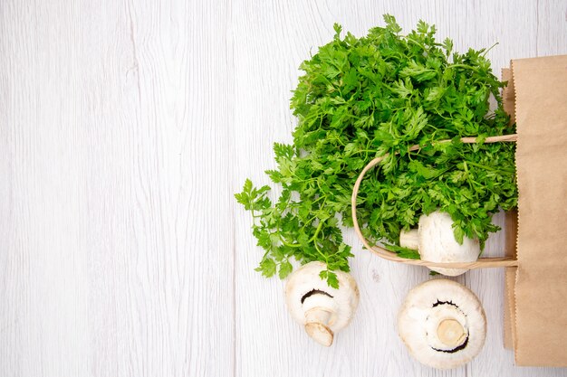 Overhead view of a bundle of fresh green mushrooms broccoli in a basket on white background