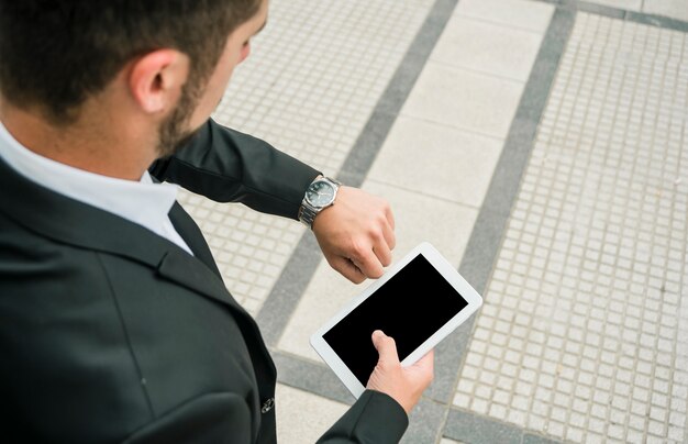 An overhead view of a businessman looking at his watch holding mobile phone in hand