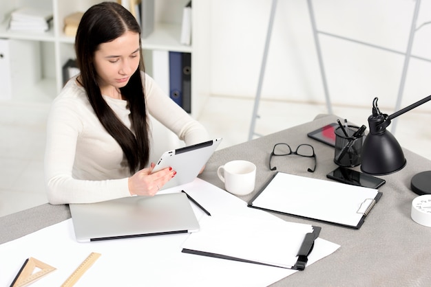 An overhead view of businesswoman looking at digital tablet at workplace