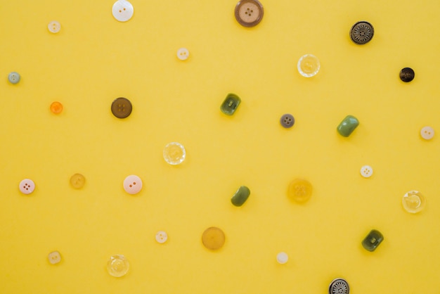 Free photo an overhead view of buttons on yellow backdrop