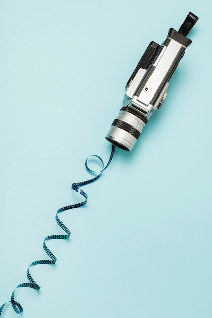 Free photo an overhead view of camcorder with swirl film stripes on blue backdrop