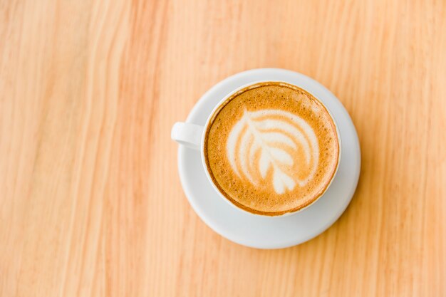 An overhead view of cappuccino coffee with art latte on wooden table