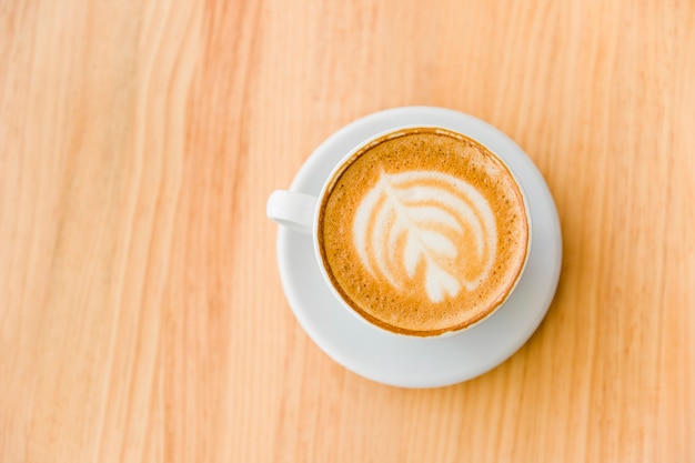Верхний вид кофе капучино с изображением латте на деревянном столе