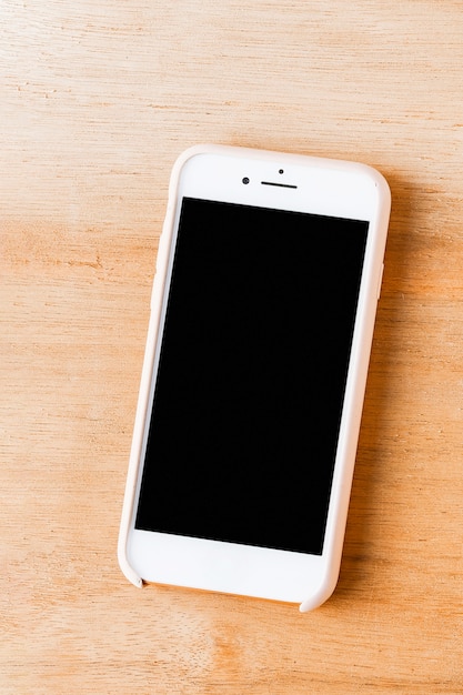 An overhead view of cellphone on wooden textured backdrop