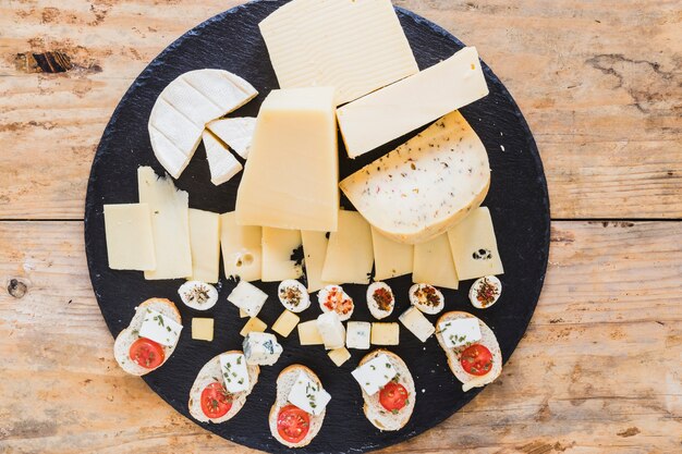 An overhead view of cheese blocks on black slate board on table