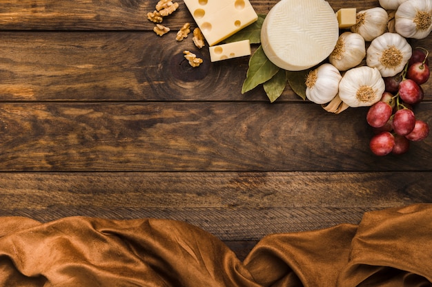 風化した木製の机の上の茶色の布とチーズと成分のオーバーヘッドビュー