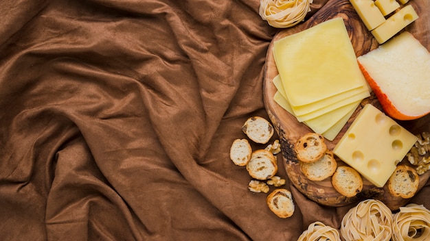 Overhead view of cheese, pasta and bread on crushed textile