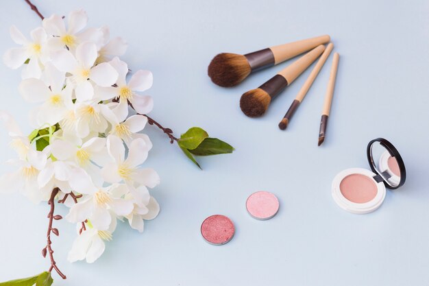 An overhead view of cherry blossom; makeup brush; blusher on colored background