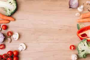 Free photo an overhead view of cherry tomatoes; mushroom; carrot; broccoli; garlic and bell pepper on wooden table with copy space for writing the text