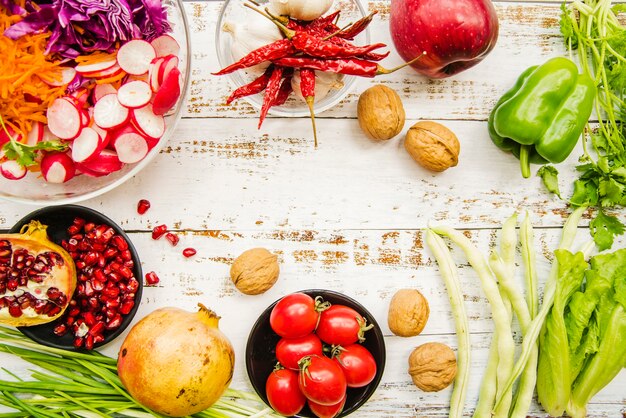 An overhead view of cherry tomatoes; red chilies; spring onion; garlic; lettuce; parsley; ripe pomegranate; reddish and walnut