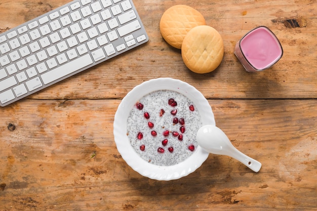 Foto gratuita una vista dall'alto di budino di semi di chia; biscotti; frullato e tastiera del computer wireless sul tavolo