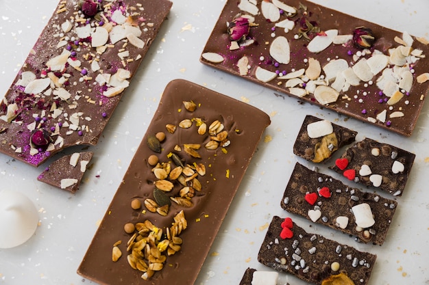 An overhead view of chocolate bar with toppings on white backdrop