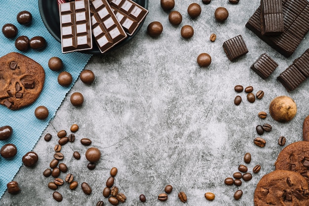 Overhead view of chocolate products with roasted coffee beans on grunge backdrop