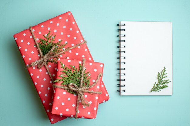 Overhead view of Christmas background with gift boxes and spiral notebook on pastel green background