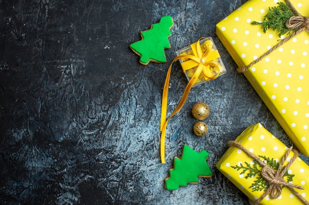 Overhead view of Christmas background with yellow gift boxes and cookies on dark background