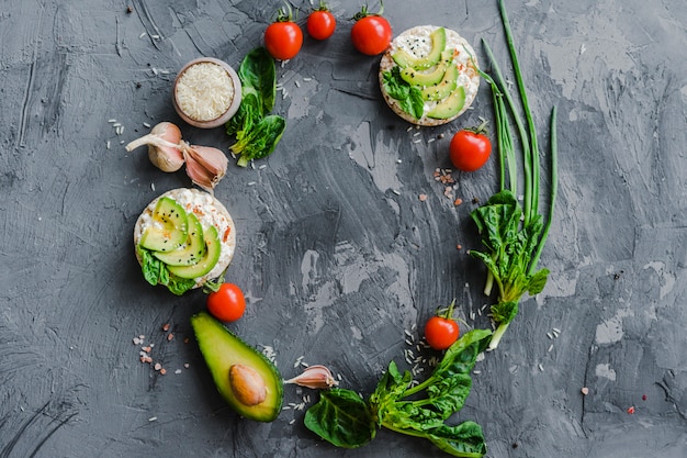 Overhead view of circular frame made with fresh vegetables over textured surface