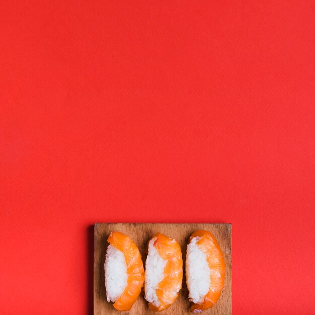 Вид сверху классические суши с лососем на разделочную доску на красном фоне