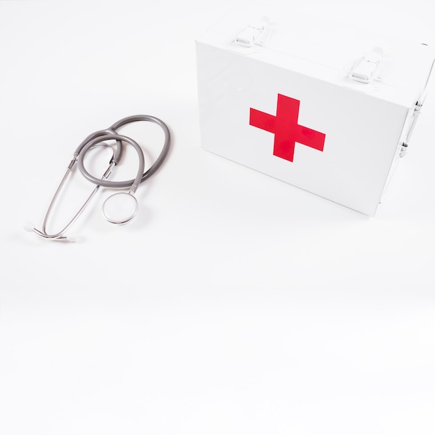 Overhead view of closed first aid kit and stethoscope on white background