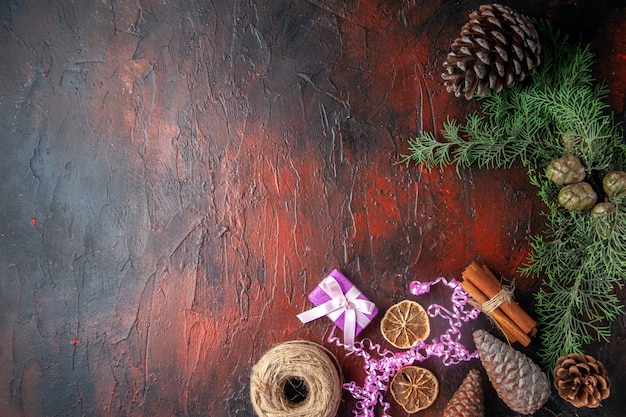 Overhead view of closed notebook with pen cinnamon limes and a ball of rope gift conifer cones on the left side on dark background