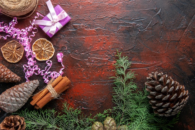 Overhead view of closed notebook with pen cinnamon limes and a ball of rope gift conifer cones on the right side on dark background