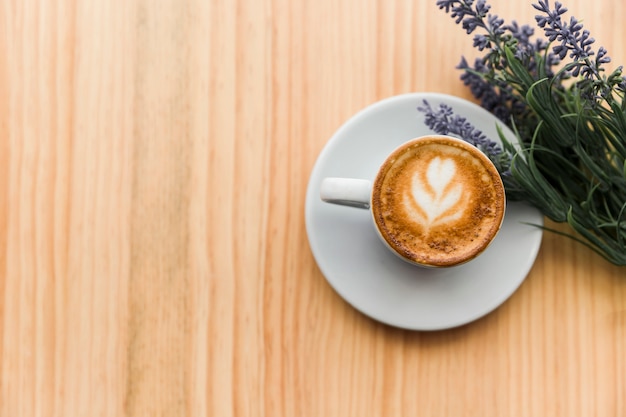 Overhead view of coffee latte with lavender flower on wooden table