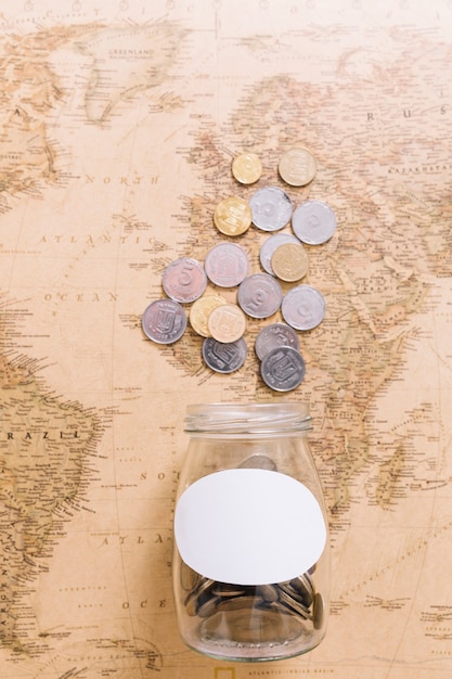 Overhead view of coins and an open jar on world map