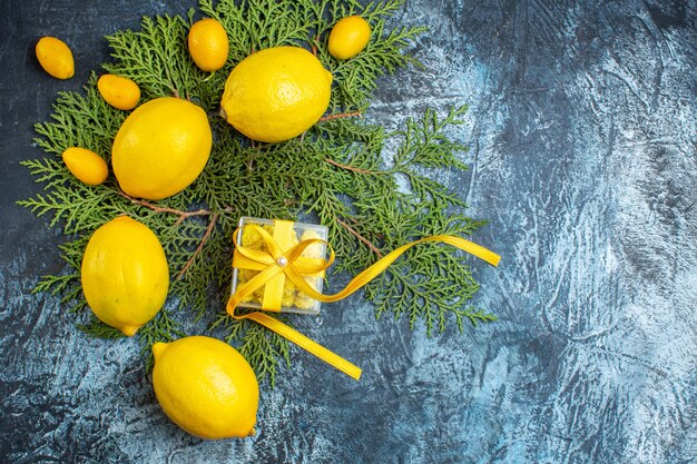 Overhead view of collection of natural organic fresh citrus fruits on fir branches and a gift box on dark background