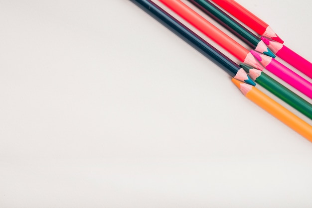 Overhead view of color pencils arranged at the corner of white background