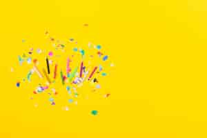 Free photo overhead view of colorful candles with confetti on yellow background