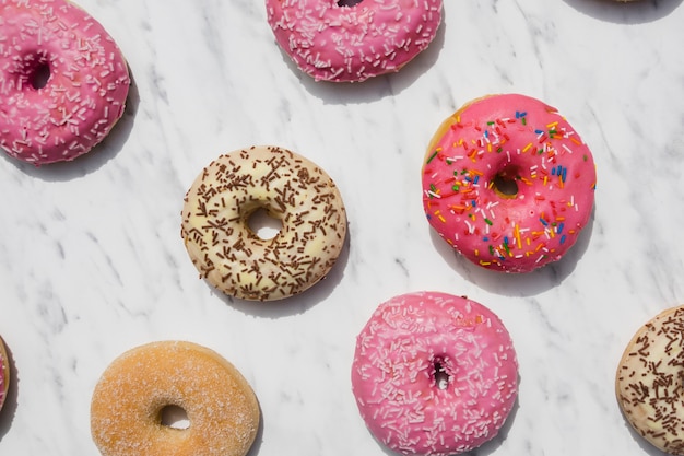 An overhead view of colorful donuts on marble textured backdrop